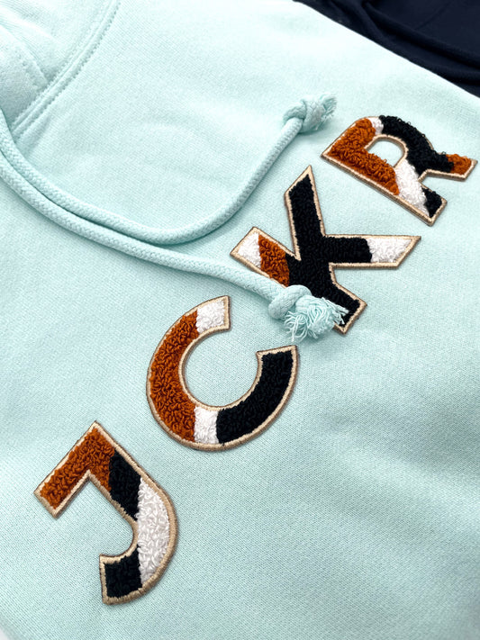 Glacial blue hoodie with JCKR chenille patch detail from up close