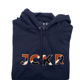 Folded navy blue hoodie with 'JCKR' branding chenille patch on a white background