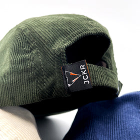 close up of green fine corduroy 5 panels hats with JCKR logo embroidered patch on the front and vowen laben on the back