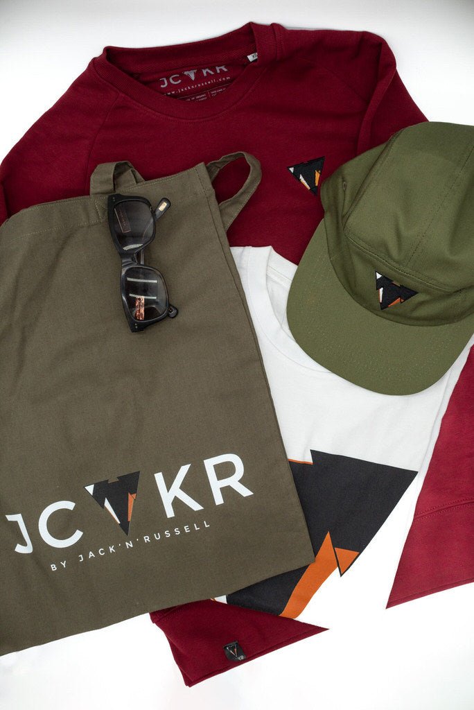Bordeaux t-shirt, green tote bag with sunglasses, green cap, and JCKR logo t-shirt