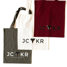 3 tote bags in different colors with the JCKR print on the front, organic cotton