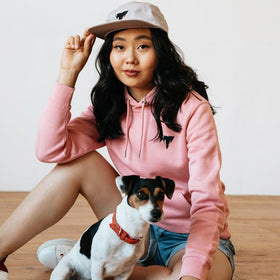Woman in pink organic cotton hoodie and cap from JCKR CLothing with a dog 