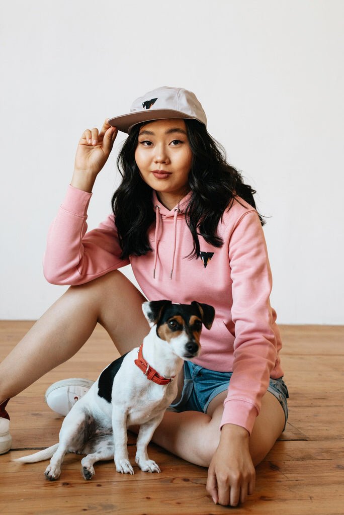 Woman in pink organic cotton hoodie and cap from JCKR CLothing with a dog 